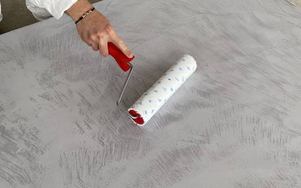 Roller application of Cerbero Base on a grey microcement surface