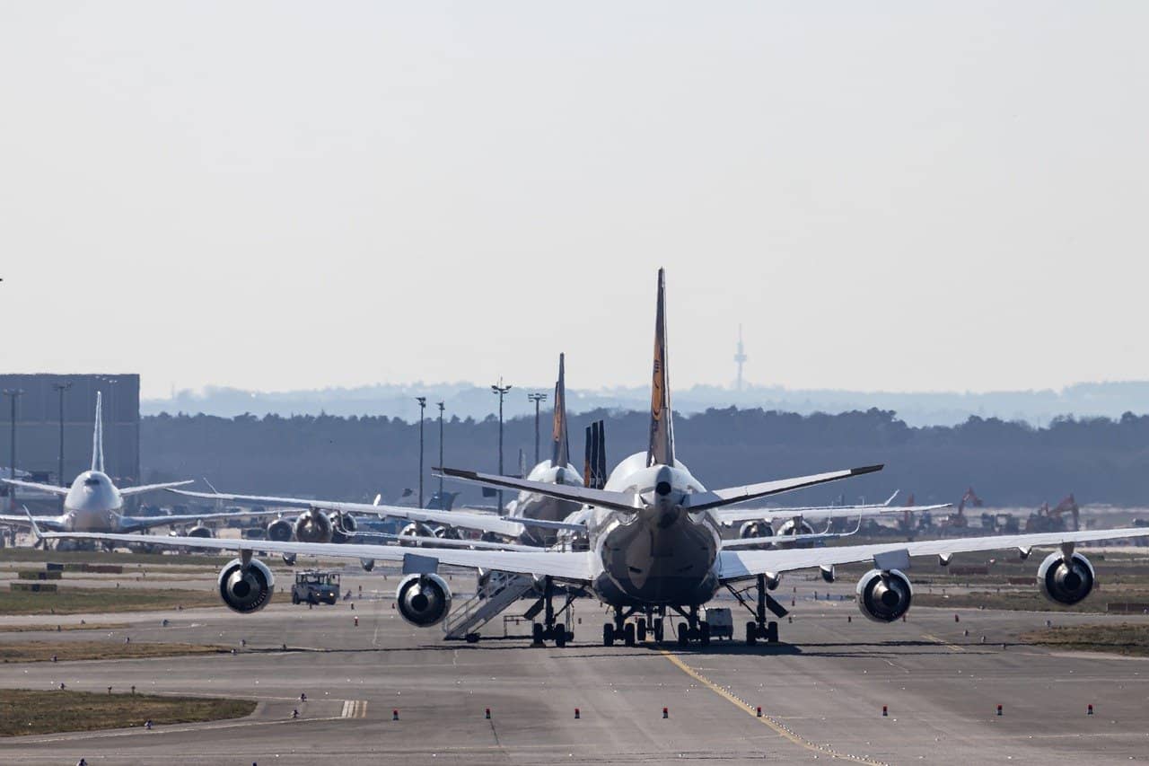 Pistă de aeroport din beton cu câteva avioane parcate