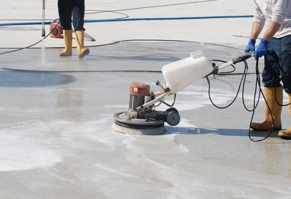 Cleaning a concrete floor with Degreaser using a scrubbing machine and a pressure washer