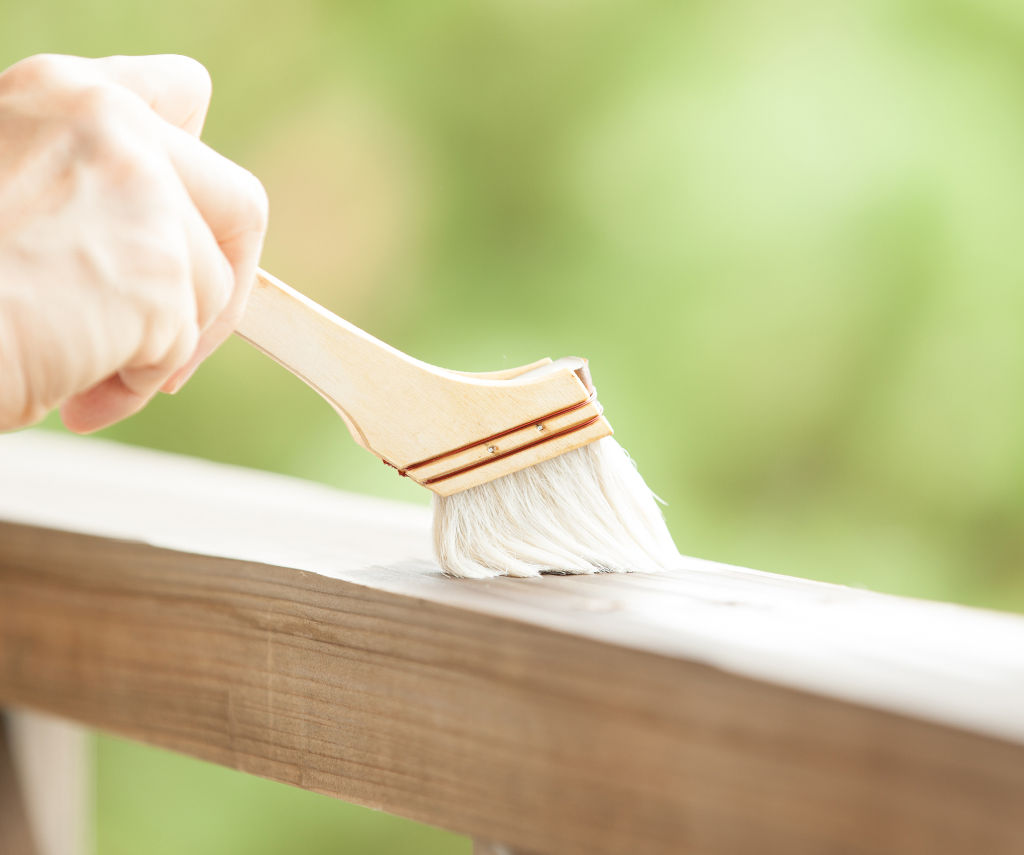 Aplicarea cu pensula a Everwood Bio Varnish pe un element de gard din lemn